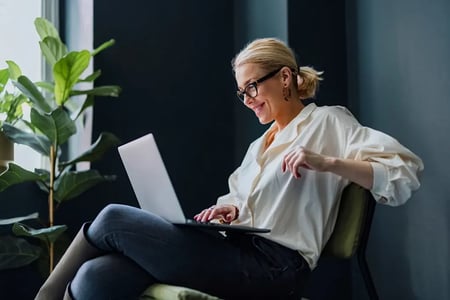 Person smiling while reading on a laptop in at their kitchen island