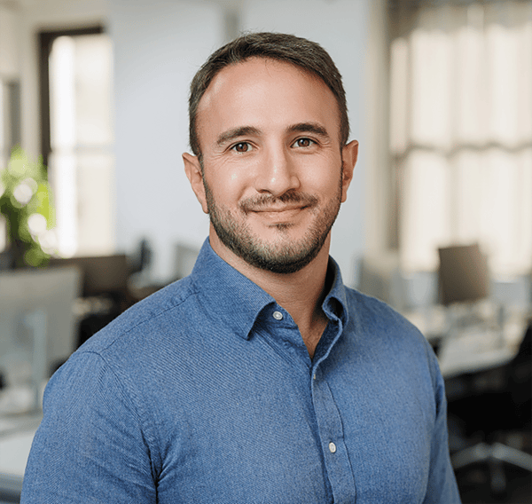 Headshot of Ben Koubek with empty office environment in background.