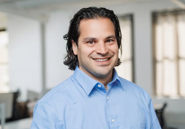 Headshot of Daniel Brundige with empty office environment in background.