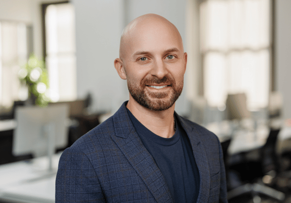 Headshot of Greg Autuori with empty office environment in background.