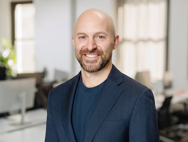 Headshot of Greg Autuori with empty office environment in background.